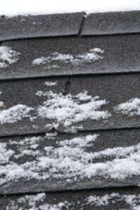 Homeowner examines scattered hail impact marks on asphalt shingles from the ground after a storm.
