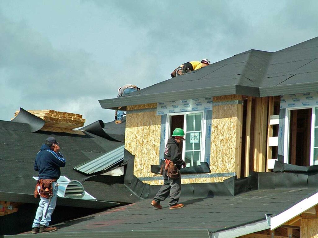A homeowner inspecting a stained attic ceiling beneath damp roof decking after a storm.